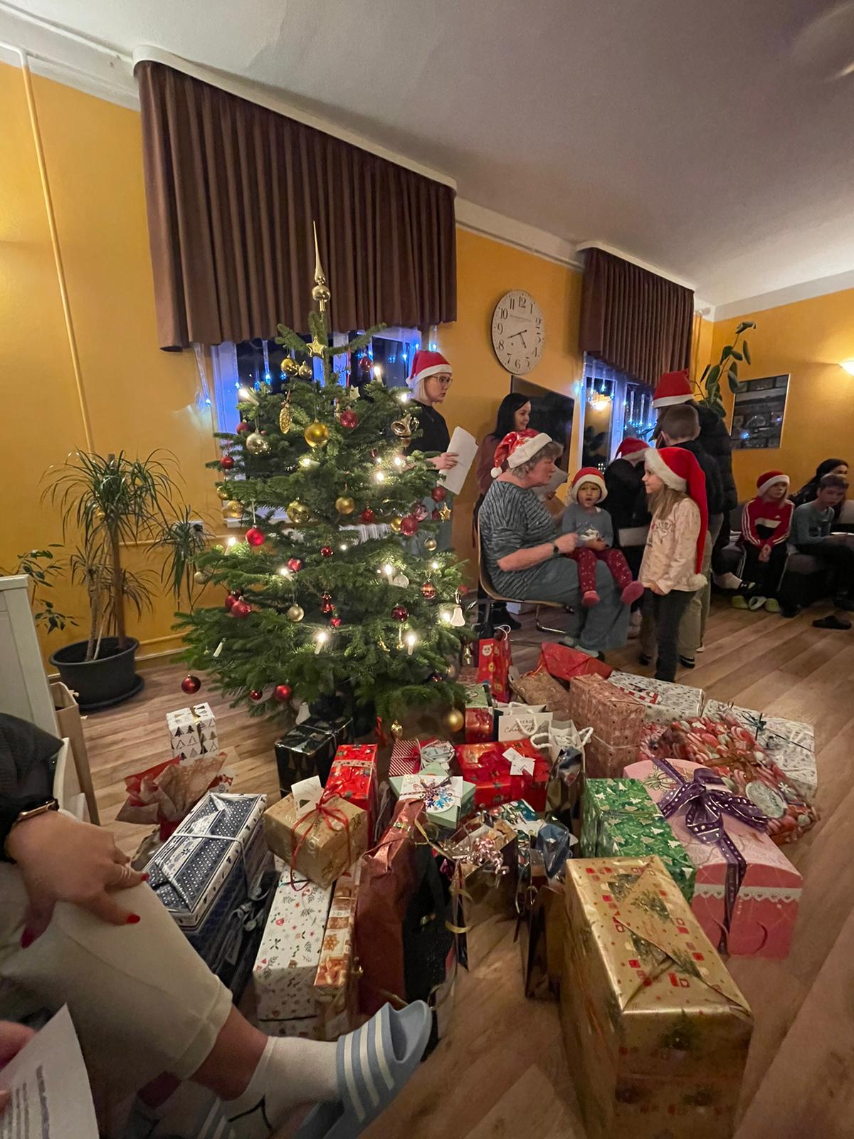 Weihnachtsbaum mit vielen Geschenken und singende Kinder